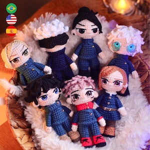 Può includere: Una collezione di sette bambole all'uncinetto fatte a mano, ognuna con acconciature e tratti del viso unici. Le bambole indossano uniformi blu con vari accenti colorati e sono disposte in un cestino intrecciato con una soffice fodera bianca. Le bambole variano in altezza.