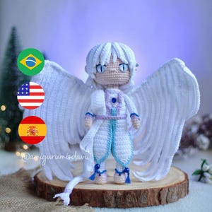 May include: White crocheted angel with blue accents and large white wings. The angel is standing on a wooden base. The image includes the text "@amigurumisdavid".