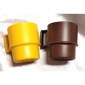 May include: Two small plastic mugs, one bright yellow and one dark brown, each featuring a textured surface, a cylindrical body with a slightly wider base section, and a square-shaped handle attached to the side of the cup.