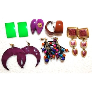 May include: A collection of vintage earrings in various styles and colors. Includes bright green rectangles, purple teardrops, brown hoops, gold-framed pink squares, dark purple crescent moons, and beaded dangle earrings.
