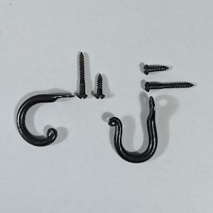 May include: A collection of black metal hooks and screws. Two hooks with curled ends are positioned on the left and right. Three screws of varying sizes are arranged above the hooks. The items are set against a neutral background.