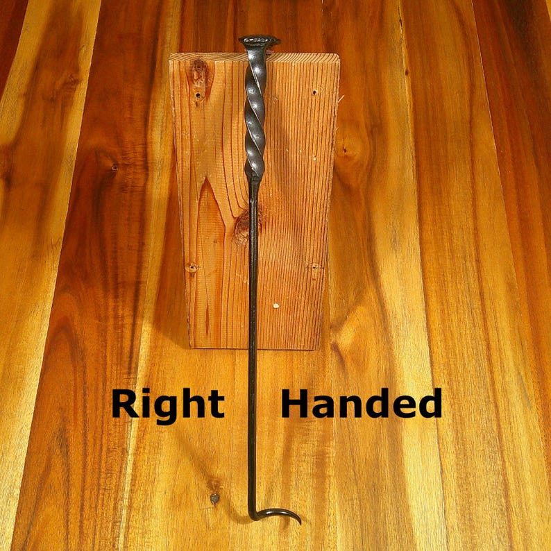 Puede incluir: Un atizador de chimenea negro para diestros, con un mango retorcido y un extremo en forma de gancho. El atizador est&aacute; montado sobre un bloque de madera, con las palabras "Right Handed" impresas debajo.