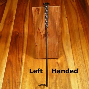Puede incluir: Un atizador de chimenea negro para zurdos con un dise&ntilde;o de mango retorcido. El atizador es de metal y tiene un gancho en el extremo. El texto "Left Handed" es visible en la imagen.