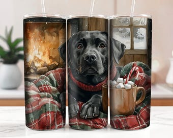 Könnte beinhalten: Ein schwarzer Labrador Retriever sitzt in einer karierten Decke vor einem Kamin mit einer Tasse heißer Schokolade und Marshmallows. Der Hund trägt einen roten Schal. Die Tasse steht auf einer rot-weiß karierten Decke.
