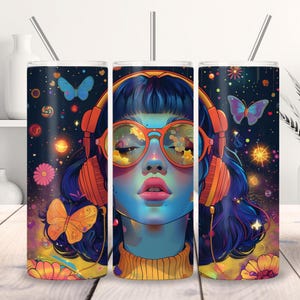 May include: A colorful tumbler featuring a vibrant illustration of a woman wearing orange headphones and glasses. The design includes butterflies, flowers, and a starry background. The tumbler has a silver straw.