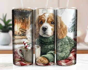 May include: A white ceramic tumbler with a green and brown dog wearing a green sweater and a red and white plaid blanket. The dog is holding a mug of hot chocolate with marshmallows and a candy cane.