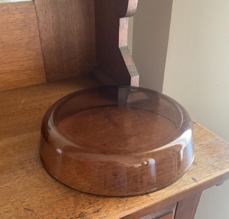 May include: A clear glass bowl with a brown tint, sitting on a wooden surface.