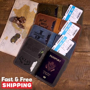 May include: Four leather passport holders in olive, brown, blue, and grey, each featuring custom engravings like 'Eat Well Travel', 'JACKSON', and 'KLS'. One grey holder contains a United States passport, while all include airline boarding passes.