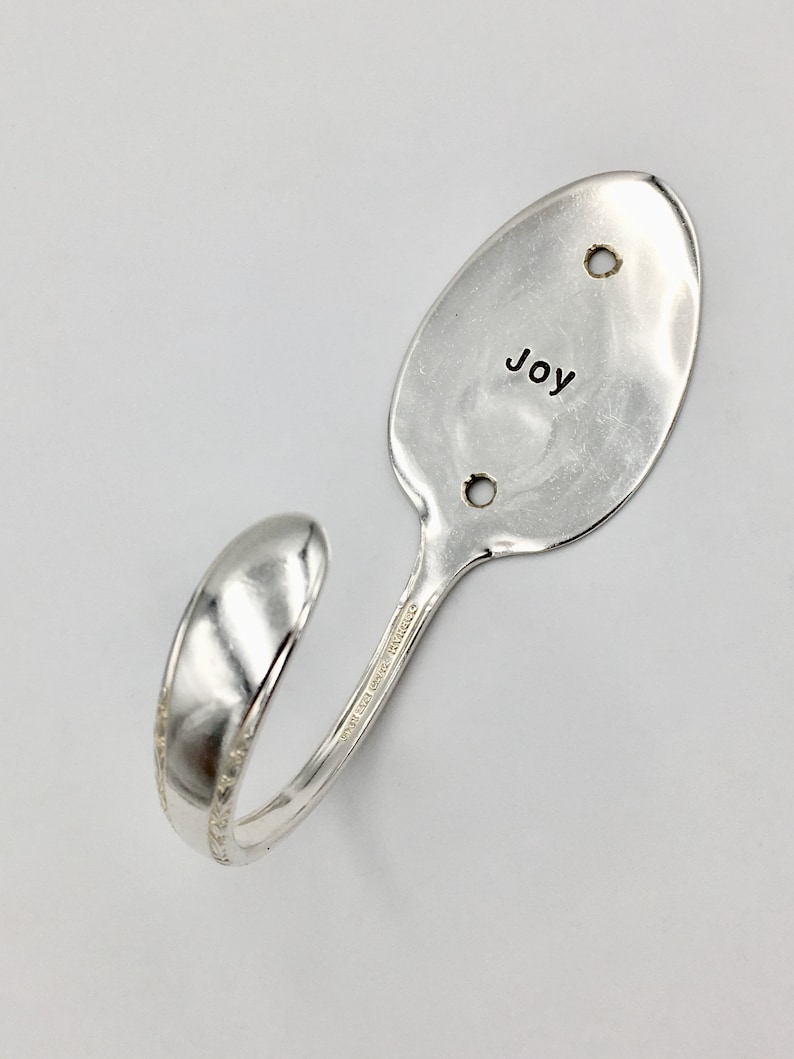 Peut inclure: Crochet en forme de cuill&egrave;re en argent avec le mot "Joy" grav&eacute; sur la partie cuill&egrave;re. La cuill&egrave;re est pli&eacute;e en forme de crochet.
