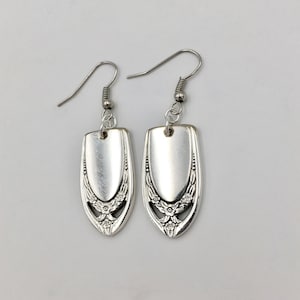 May include: A pair of silver earrings with a floral design. The earrings are made from repurposed silverware.