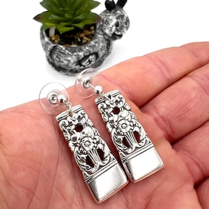 Puede incluir: Un par de pendientes de plata con un diseño floral. Los pendientes están hechos de cubiertos reutilizados y tienen un aspecto vintage.