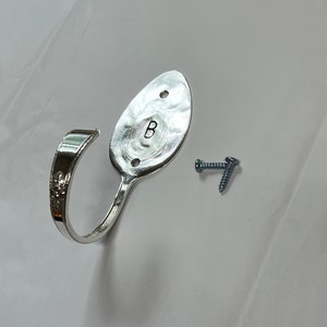 Peut inclure: Un crochet en forme de cuill&egrave;re en argent avec la lettre "B" grav&eacute;e au dos. Le crochet est fix&eacute; au mur avec deux vis.