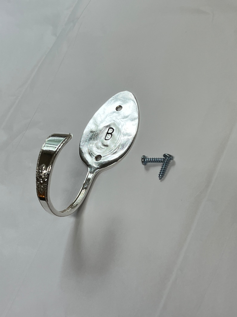 Peut inclure: Un crochet en forme de cuill&egrave;re en argent avec la lettre "B" grav&eacute;e au dos. Le crochet est fix&eacute; au mur avec deux vis.
