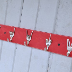 Puede incluir: Perchero de pared de madera roja con cinco ganchos de metal plateado en forma de tenedores.