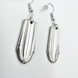 May include: A pair of silver earrings made from vintage silverware. The earrings are shaped like a spoon and have a decorative design.