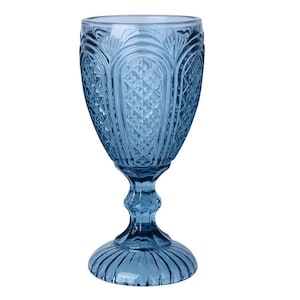 Könnte beinhalten: Ein blaues Glasgoblet mit einem dekorativen, geprägten Muster. Das Goblet hat einen hohen, schlanken Stiel und eine breite, runde Schale.