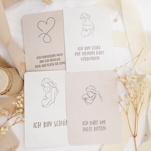 May include: Four rectangular affirmation cards with rounded corners, featuring line art illustrations and German text. The cards display drawings of a pregnant person and a parent with a baby, alongside phrases about strength, beauty, and asking for help.