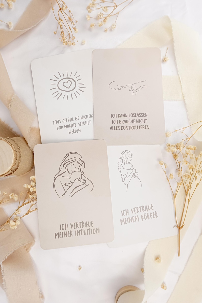 May include: Four rectangular affirmation cards with line art illustrations and German text. The cards feature drawings of a sun with a heart, reaching fingers, a person holding a baby, and a pregnant person, with phrases about intuition and trust.