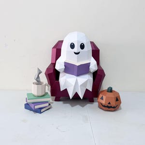Może przedstawiać: Papierowy duch typu low-poly z białym ciałem i czarnymi oczami siedzi w ciemnoczerwonym fotelu, czytając fioletową książkę. Obok fotela znajduje się stos trzech książek w kolorze zielonym, fioletowym i niebieskim, beżowy kubek z szarą parą oraz pomarańczowa dynia.