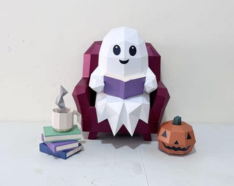 May include: A low-poly papercraft ghost with a white body and black eyes sits in a dark red armchair reading a purple book. Beside the chair is a stack of three books in green, purple, and blue, a beige mug with gray steam, and an orange pumpkin.