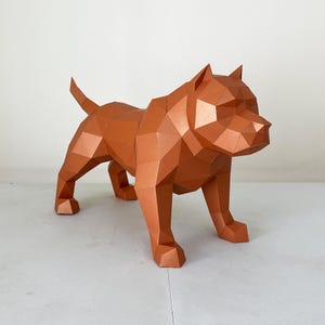 May include: A geometric, copper-coloured paper sculpture of a dog in a standing pose. The dog's form is constructed from numerous flat, angular planes, giving it a faceted appearance. The sculpture has a tail and pointed ears.