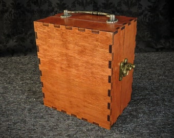 May include: A wooden box with a hinged lid, a brass handle, and a brass latch. The box is made of a light brown wood with a smooth finish.