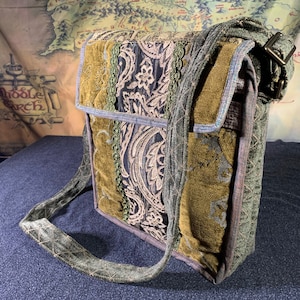 Puede incluir: Un bolso bandolera de patchwork verde, marrón y negro con una correa larga ajustable. El bolso tiene cierre de solapa y un diseño bordado decorativo.