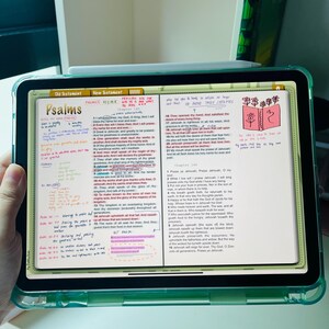 May include: A close-up of a digital tablet displaying an open Bible app. The screen shows the book of Psalms with highlighted verses and handwritten notes. The app interface includes tabs for "Old Testament" and "New Testament".