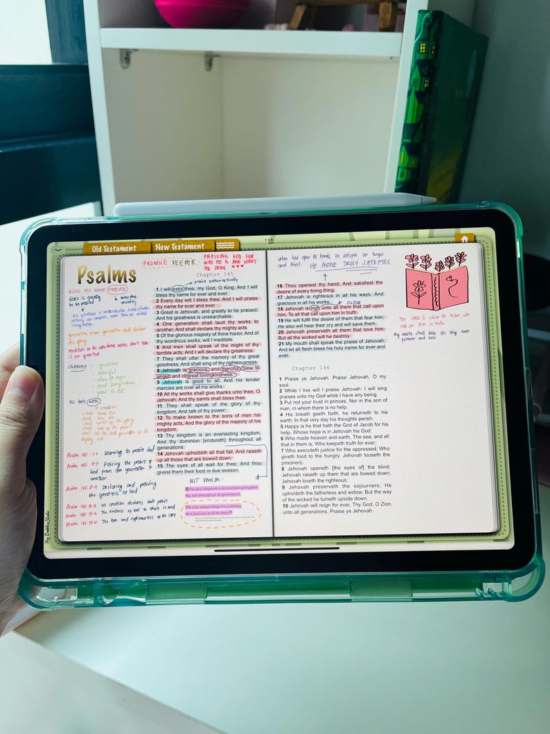 May include: A close-up of a digital tablet displaying an open Bible app. The screen shows the book of Psalms with highlighted verses and handwritten notes. The app interface includes tabs for "Old Testament" and "New Testament".