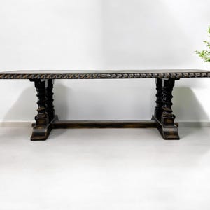 May include: A dark brown wooden dining table with a carved top and twisted legs. The table is standing on a white floor.