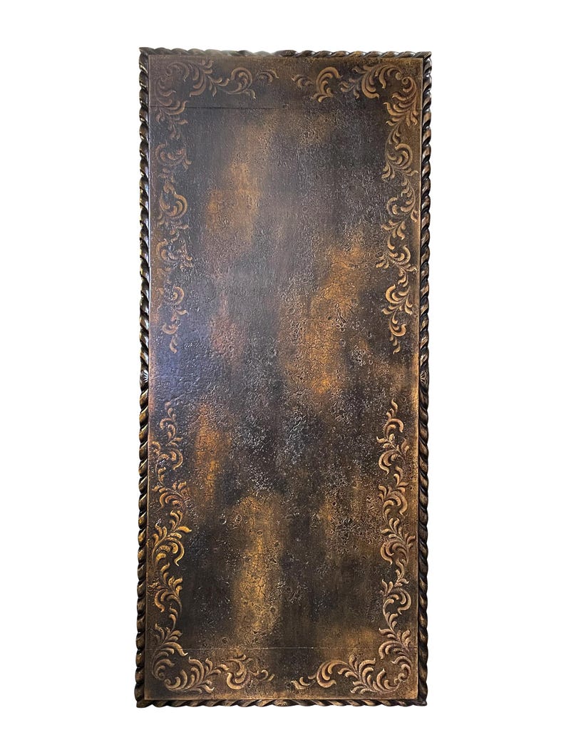 May include: A dark brown rectangular table top with a decorative border of rope and floral designs. The table top has a distressed, aged look.