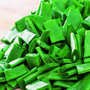 A pile of fresh green snap peas on a wooden surface.