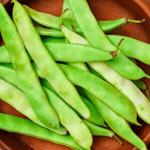 A wooden bowl filled with fresh green beans.