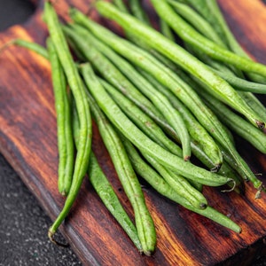 a wooden cutting board topped with green beans