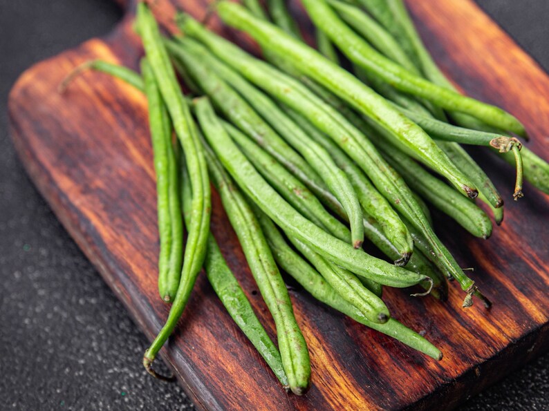 a wooden cutting board topped with green beans