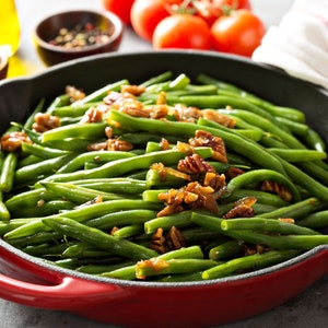 a pan filled with green beans and walnuts