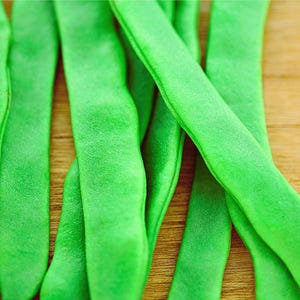 A close-up image of green beans on a wooden surface.