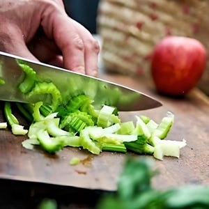 May include: A person is chopping celery on a wooden cutting board with a silver knife. The celery is chopped into small pieces and is green in color.