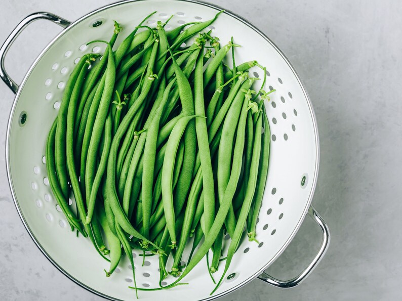 a colander filled with green beans on a table