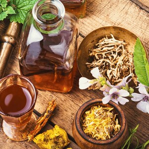 various Medicinal Marshmallow herbs, spices, and a glass of liquid on a wooden surface, suggesting a collection of natural ingredients or a display of culinary items.
