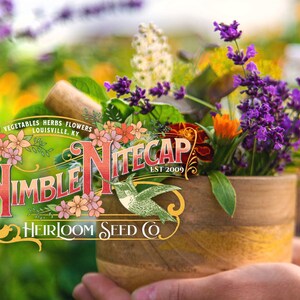 A hand holding a wooden pot filled with a variety of colorful flowers, including purple lavender, orange marigolds, and white and yellow flowers. The pot is placed on a table, and the background is blurred, suggesting an outdoor setting. Also included is the logo for Nimble NiteCap Heirloom Seed Co.