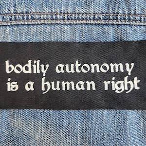 Puede incluir: Parche negro con texto blanco que dice "la autonomía corporal es un derecho humano".