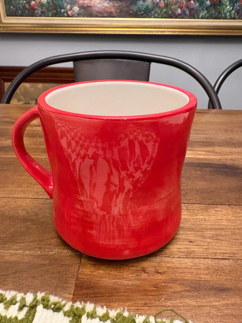 May include: A set of three ceramic mugs with a speckled, cream-colored glaze. Each mug features a different hand-painted floral design in shades of blue, green, and yellow. The mugs have a simple, rounded shape and a comfortable handle.