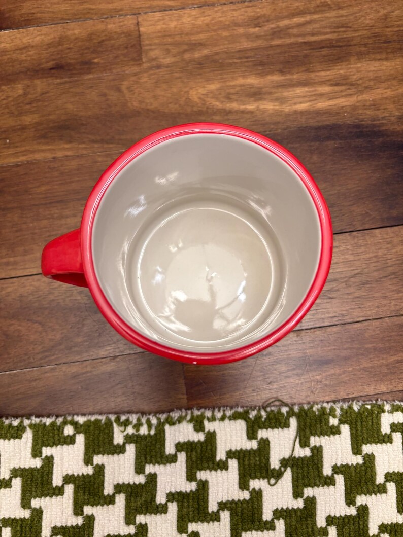 May include: A white ceramic mug with a black handle and the text "But First, Coffee" in a bold, black font. The mug is sitting on a wooden surface. The mug is approximately 4 inches tall.
