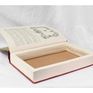 May include: A book with a hidden compartment. The book is open, revealing a cork-lined interior. The book is bound in red and green fabric.