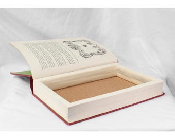 May include: A book with a hidden compartment. The book is open, revealing a cork-lined interior. The book is bound in red and green fabric.