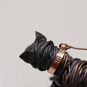 May include: A wire sculpture of a cat with a copper tag that reads "1124".