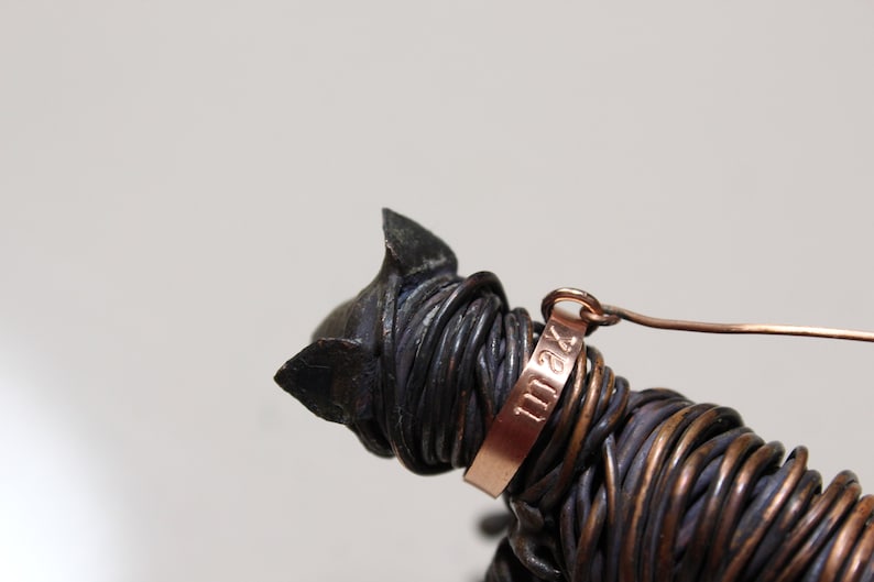 May include: A wire sculpture of a cat with a copper tag that reads "1124".