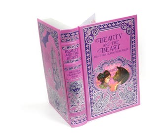 May include: A pink hardcover book with a silver and purple design. The title is "Beauty and the Beast and Other Classic Fairy Tales".