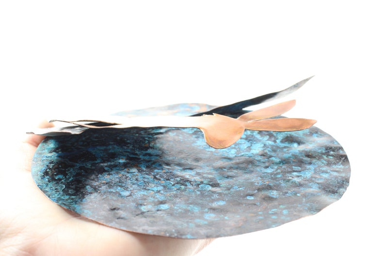 K&ouml;nnte beinhalten: Eine abstrakte Skulptur aus Kupfer und Silber mit einer blauen Patina. Die Skulptur hat die Form eines Vogels mit ausgebreiteten Fl&uuml;geln.